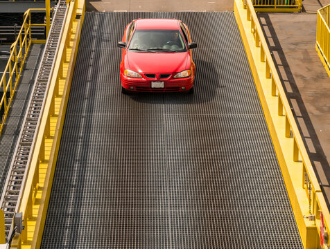 Canada, BC, Port McNeil.   Red automobile driving over metal ramp to BC Ferry, sailing to Alert Bay.