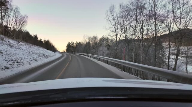 Dashboard camera view from a white car driving through  a rural winter landscape in Straumsnes, near Kristiansund, Norway.