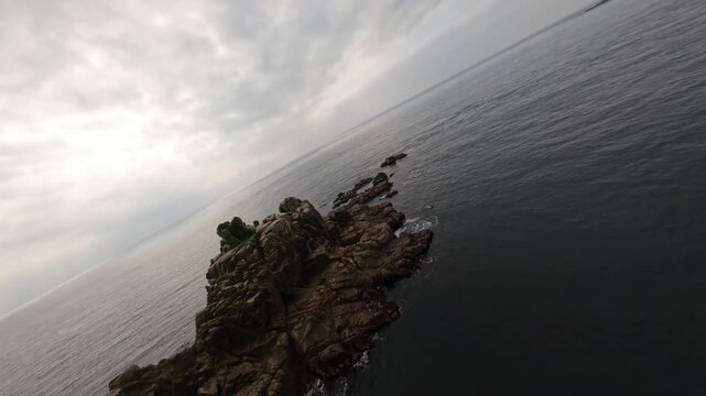 Atmospheric Aerial View of a Lonely Rocky Islet in th Calm Sea Under Overcast Sy