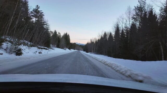 Dashboard camera view from a white car driving through a rural winter landscape at Angvika, near Kristiansund, Norway.