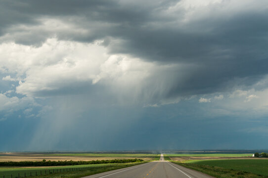 Canada, Alberta, Mossleigh.  Long, straight, prairie road, draped in light. 