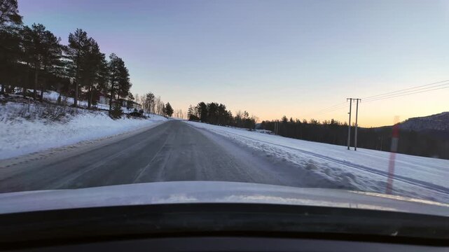 Dashboard camera view from a white car driving through a rural winter landscape at Angvika, near Kristiansund, Norway.