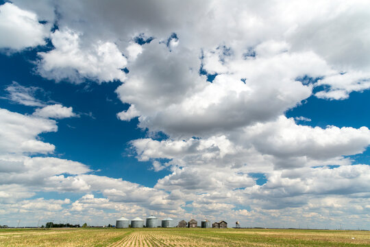 Canada, Saskatchewan, Regina.  A line of steel storage bins and equipment sheds along the horizon in the great plains of the Canadian prairies.