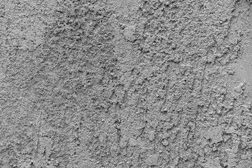 Close-up photo of gray cement or concrete wall with rough bumpy surface texture, selective focus