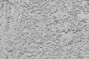 Obraz premium Macro photography of plastered concrete wall with coarse grainy texture and irregular surface pattern showing cement plaster finish, selective focus