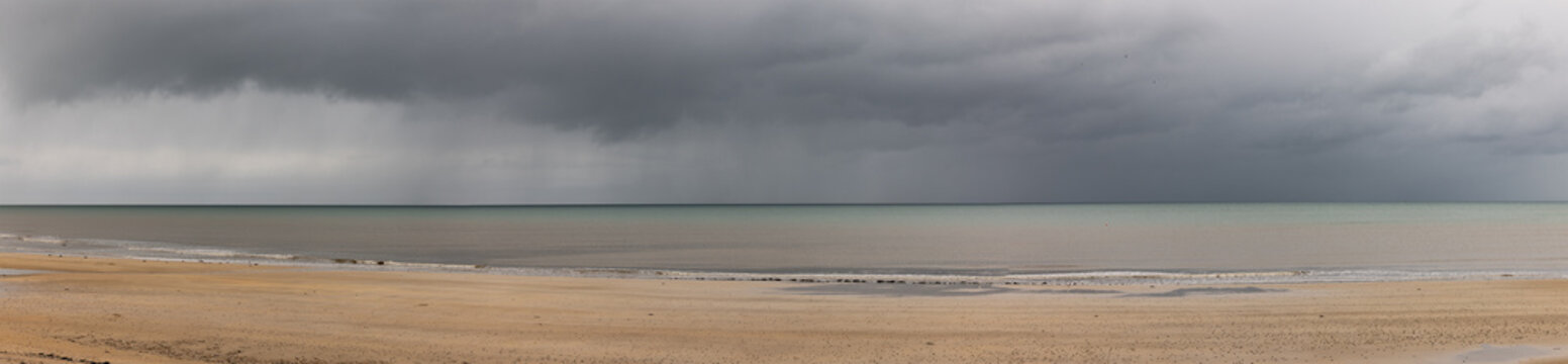 image panoramique montrant une plage d&eacute;serte sous un orage en Normandie.