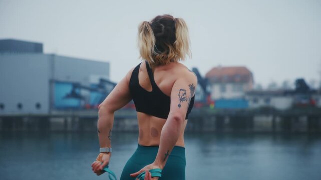 Tattooed Fit Woman Preparing Resistance Band Outdoor Foggy Day