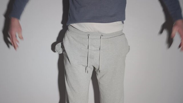 
Man Pulling Out Empty Pockets of Gray Sweatpants | No Money, Financial Problem and Poverty Concept | Broke, Debt and Economic Crisis Symbol on White Background
