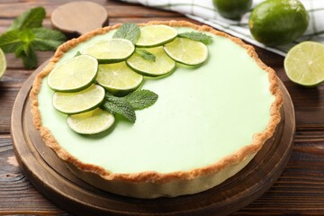 Tasty lime pie with fruit slices and mint leaves on wooden table, closeup © New Africa