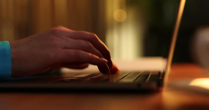 Woman working on laptop at desk indoors, closeup
