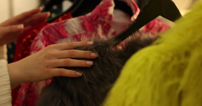 Woman choosing festive clothes on rack in dressing room, closeup. Camera moving right