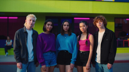 Obraz premium A group of young people standing in front of a colorful building at night