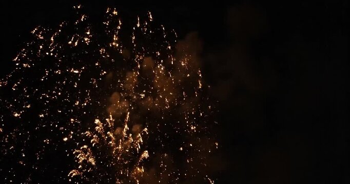 Golden fireworks exploding brightly in dark night sky celebration