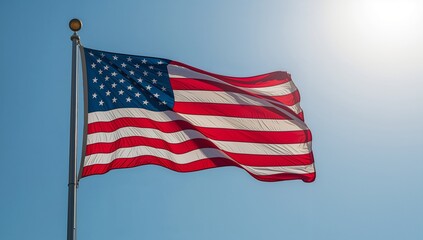 Obraz premium The American Flag Waving Proudly in a Clear Blue Sky on a Sunny Day