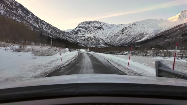 Dashboard camera view from a white car driving through the rural winter wonderland of Oeksendalen valley, near Kristiansund, Norway.