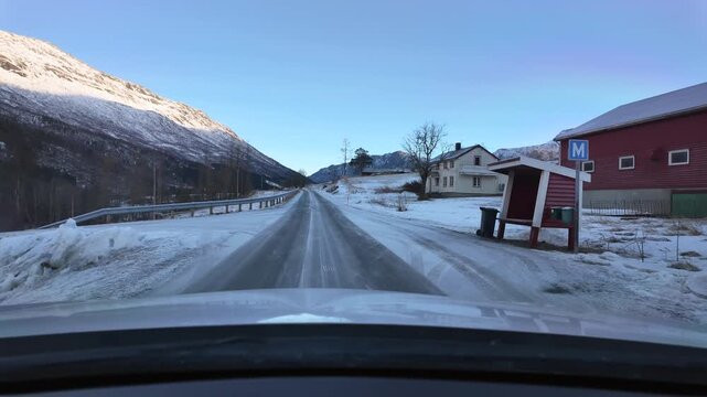 Dashboard camera view from a white car driving through the rural winter wonderland of Oeksendalen valley, near Kristiansund, Norway.