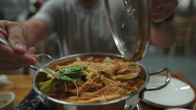 Steam Rises As Noodles Settle In Bowl. Serving Hotpot With Rising Steam And Inviting Atmosphere. Closeup Of Ladle Pouring Hot Broth Into Bowl Amid Fragrant Steam And Inviting Ambiance