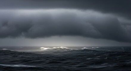 Fototapeta premium Heavily laden storm clouds casting dramatic shadows over a churning, dark ocean with powerful waves.