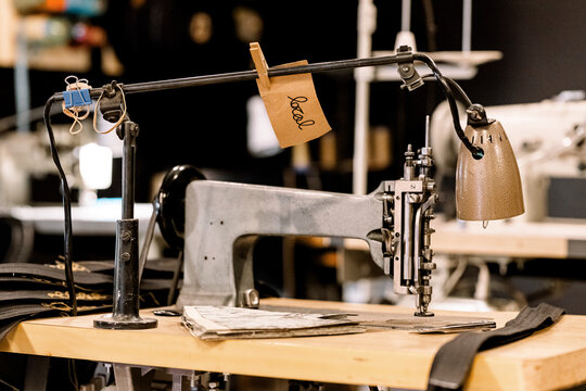 Sebuah alat mesin jahit antik dari logam dan kayu dengan jarum serta benang untuk produksi pakaian industri yang menunjukkan keahlian menjahit tua yang autentik