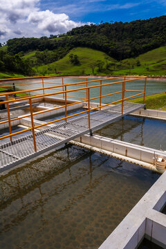 Water purification process at a treatment plant. Industrial facility with settling tanks ensuring clean water supply and environmental protection, with green hills in the background. 
