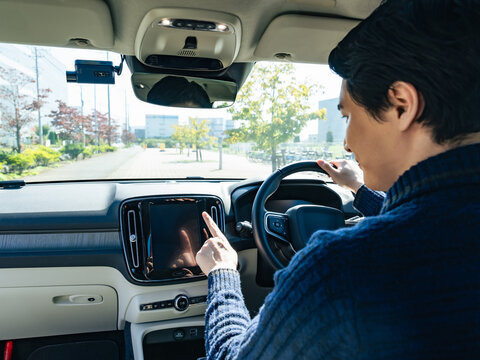 自動車のインパネ画面をタッチするドライバー