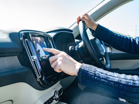 自動車のインパネ画面をタッチするドライバー