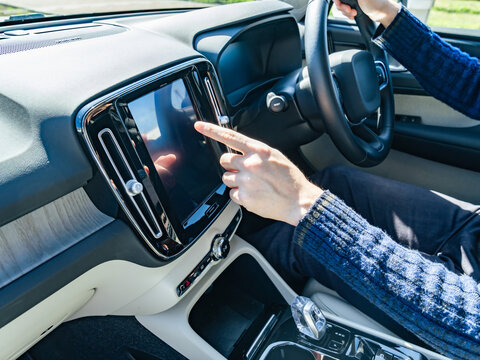 自動車のインパネ画面をタッチするドライバー