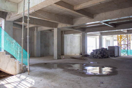 Jakarta, Indonesia - March 16, 2026: Building interior room under construction with concrete stairs, water puddle on floor, lightweight brick stacks and iron scaffolding