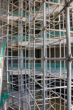 Jakarta, Indonesia - March 16, 2026: Intricate steel scaffolding frame structure supporting an unfinished high-rise building construction area.