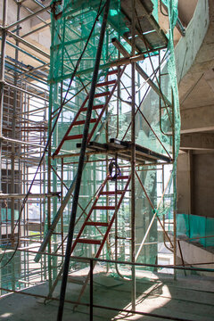 Jakarta, Indonesia - March 16, 2026: Red portable access stairs installed between scaffolding structures in a building construction area.