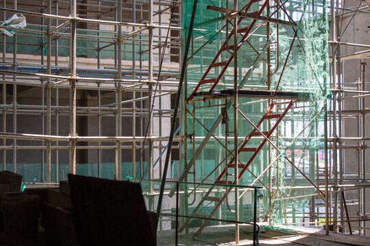 Jakarta, Indonesia - March 16, 2026: Detail of red access stairs and metal scaffolding system inside a building project under construction.