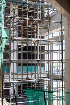 Jakarta, Indonesia - March 16, 2026: Iron scaffolding frame and building concrete under construction with green safety netting in a Jakarta project area