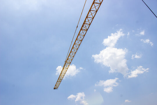 Jakarta, Indonesia - March 16, 2026: Long steel jib of a yellow tower crane extending over a building construction project site.