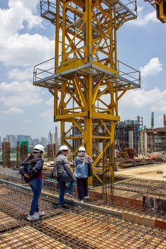 Jakarta, Indonesia - March 16, 2026: A group of engineers and construction workers wearing hard hats walking on an ongoing building construction site.