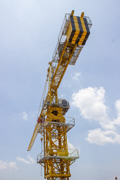 Jakarta, Indonesia - March 16, 2026: Low angle view of a towering yellow crane with counterweights at the top at a construction site.