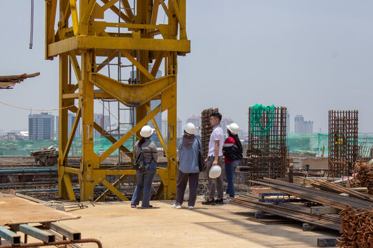 Jakarta, Indonesia - March 16, 2026: A group of construction workers discussing on a building project floor with city view background