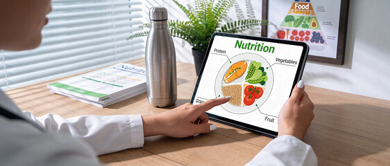 Professional Nutritionist or Dietitian Using a Digital Tablet to Explain a Healthy Balanced Diet Plate and Nutrition Plan to a Patient in a Modern Healthcare Clinic or Wellness Office Setting.