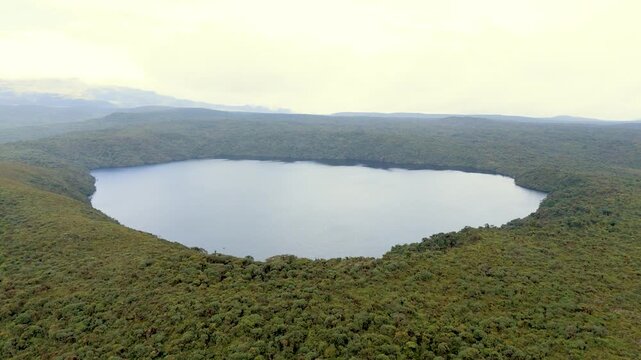 A serene aerial shot of Buey Lagoon nestled within dense greenery, illustrating a tranquil landscape under overcast skies.