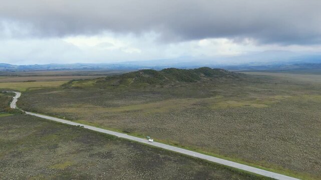 Wide landscape featuring a winding road and distant hills under an overcast sky. Visuals showcase the rugged terrain of the national park.