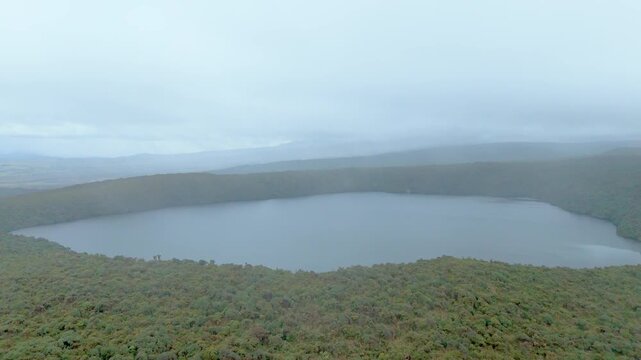 An aerial view of Buey Lagoon surrounded by green vegetation under a cloudy sky in Purace National Park.