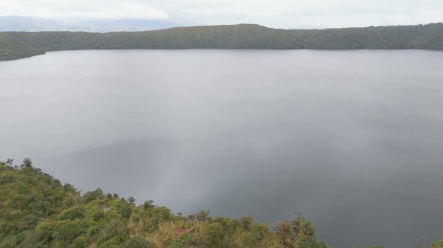 A tranquil view of Buey Lagoon within Purac&eacute; National Park, framed by lush vegetation and a reflective surface under overcast skies.