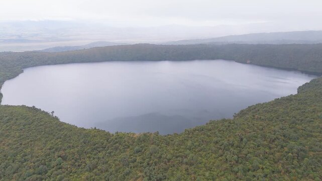The tranquil waters of Buey Lagoon reflect the surrounding lush greenery and overcast sky in this aerial shot.