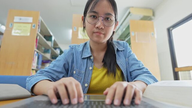 Student working on laptop in a library study session educational environment focused viewpoint