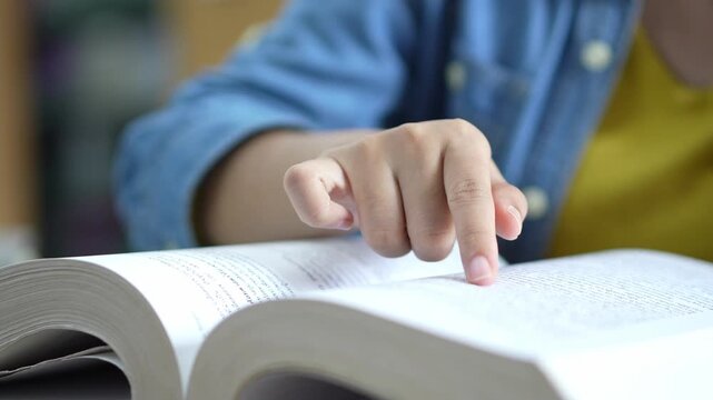 Studying in a library student engaged with textbook academic environment close-up focus learning process