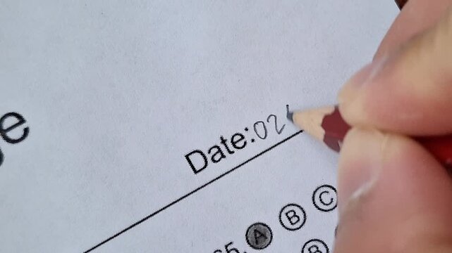 Hand writes date on lined paper with pencil