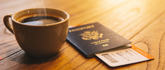 Fototapeta premium Close-up of a steaming cup of coffee, a passport, and a boarding pass on a rustic wooden table bathed in warm golden sunlight, capturing the anticipation of travel, vacation, and global adventure.