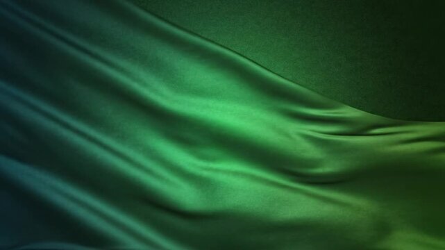 Luxurious emerald green silk fabric waving slowly against a textured background with subtle lighting and shadows