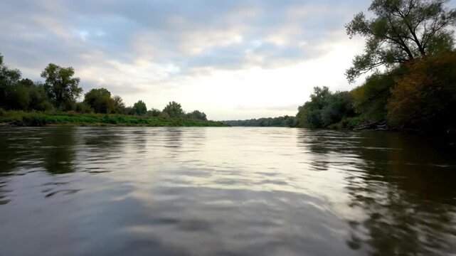 Scenic river flowing through a forested landscape on a cloudy day with tranquil water reflections