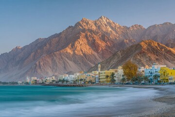 Coastal Middle Eastern town with white buildings and minaret located at the base of majestic mountains during sunset for desert tourism and travel advertising background