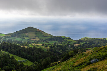 Green mountain landscape on San Miguel Island, Azores. Lush fields and wild terrain. Cloudy sky over the Atlantic Ocean coastline. © Eugene Ga